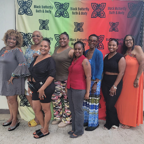 Group of women posing in front of a Black Butterfly Bath & Body banner.
