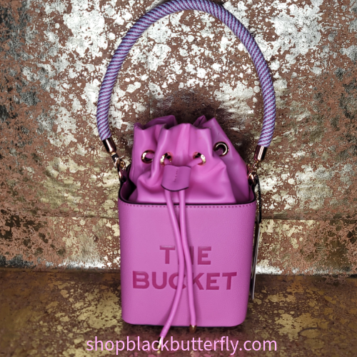 Pink bucket bag with 'The Bucket' text on a textured metallic background